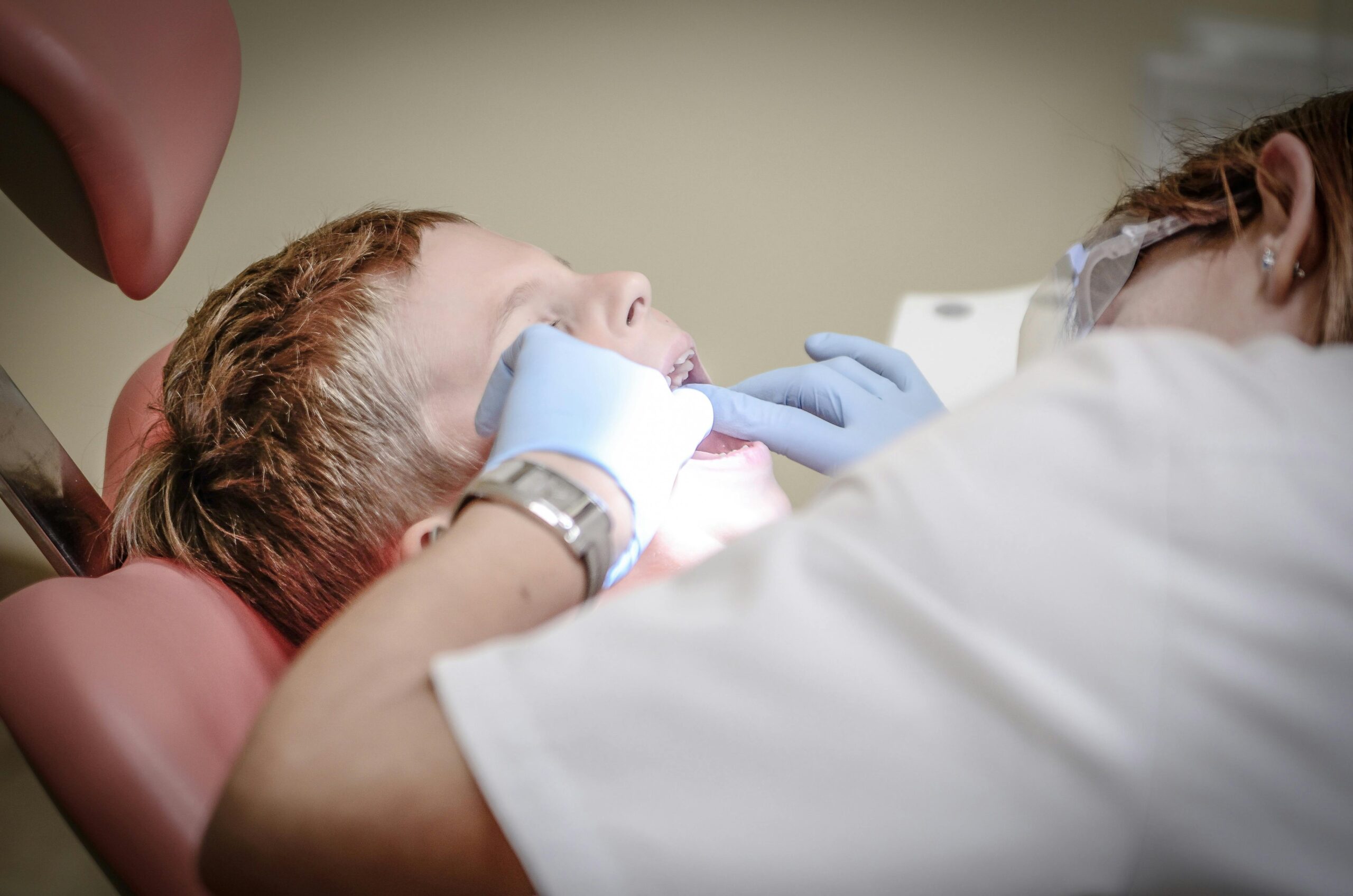 A young boy receiving a dental examination by a professional dentist in a clinic setting.