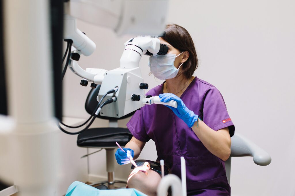 Female dentist using a microscope and modern technology during a patient examination in a dental clinic.