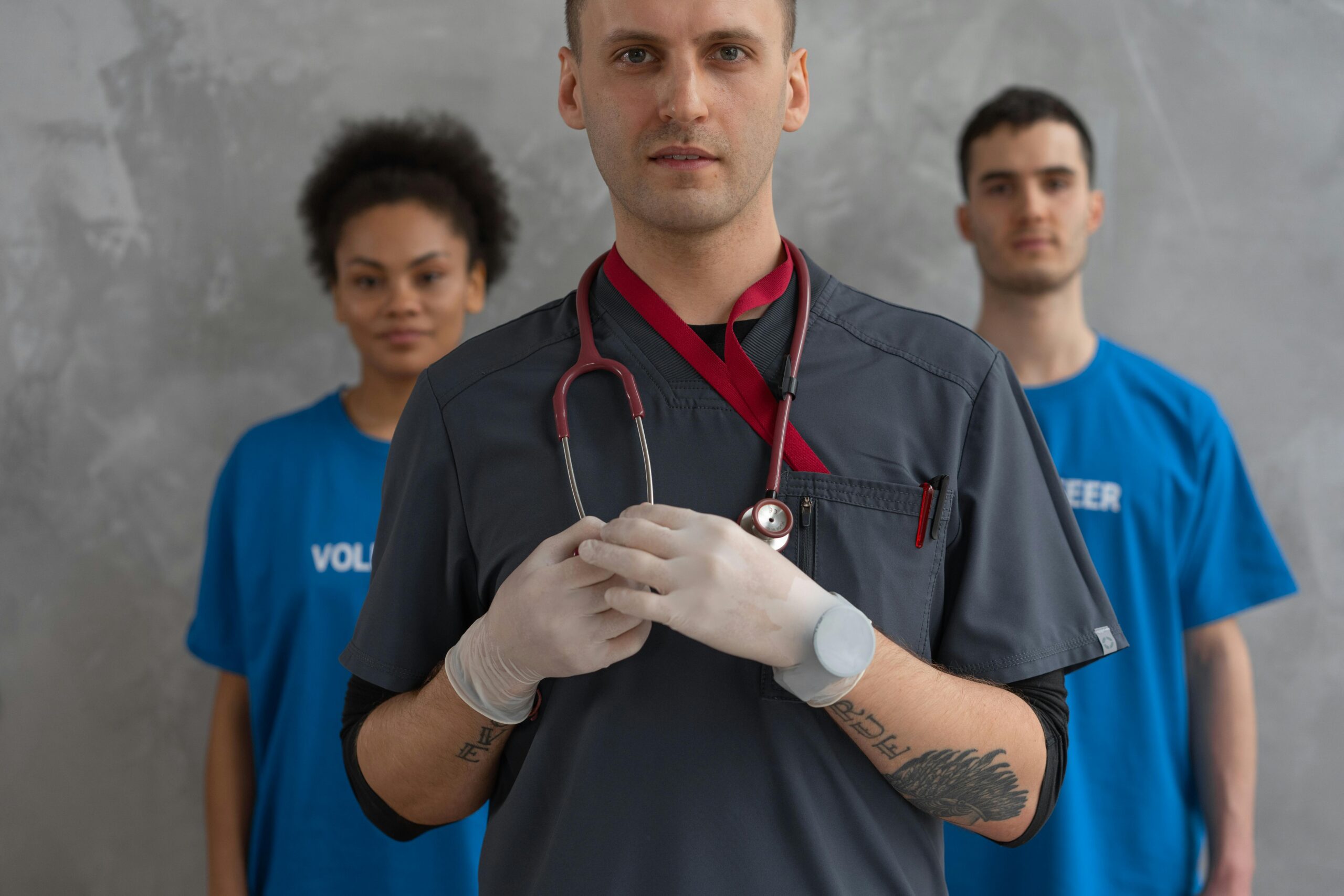 Portrait of a healthcare professional with volunteers in blue shirts, showing teamwork.